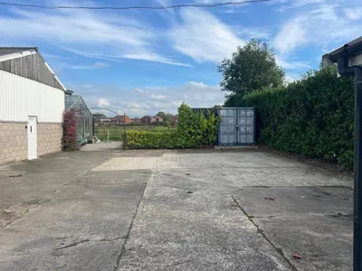 an empty parking lot with a greenhouse in a yard at The Old Lambing Barn in Longton