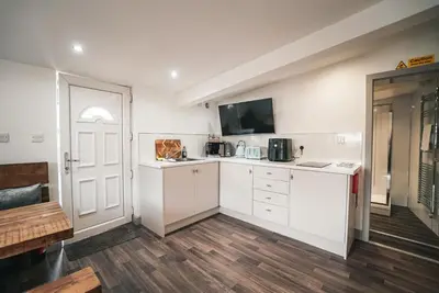 a kitchen with white cabinets and a tv on the wall at The Old Lambing Barn in Longton