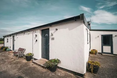 a white building with a door and a chair at The Old Lambing Barn in Longton