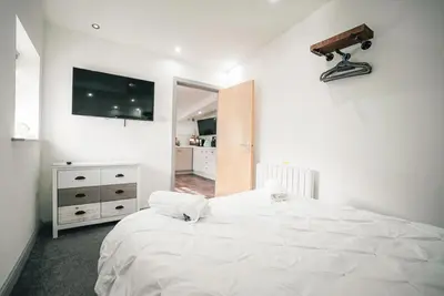 a white bedroom with a large bed with a camera on the wall at The Old Lambing Barn in Longton