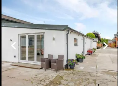 a white building with two chairs in a courtyard at The Cow Shed in Longton