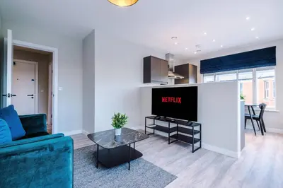 a living room with a tv and a couch and a table at Elysée Suites - Spacious 1 Bed Flat in Southport in Southport