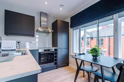 a kitchen with blue cabinets and a table with chairs at Elysée Suites - Spacious 1 Bed Flat in Southport in Southport