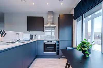 a kitchen with blue cabinets and a black table at Elysée Suites - Spacious 1 Bed Flat in Southport in Southport