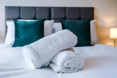 a pile of white towels on a bed at Elysée Suites - Spacious 1 Bed Flat in Southport in Southport