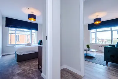 a bedroom with a bed and a room with windows at Elysée Suites - Spacious 1 Bed Flat in Southport in Southport