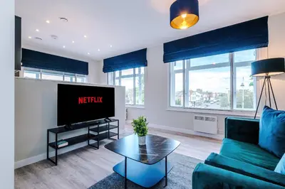 a living room with a blue couch and a tv at Elysée Suites - Spacious 1 Bed Flat in Southport in Southport