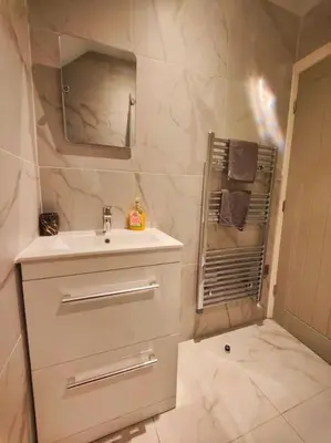 a white bathroom with a sink and a mirror at Chelsea 2 bedroom promenade apartment in Blackpool