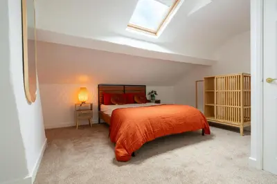 a bedroom with a bed with an orange bedspread at Liverpool Luxe Retreat 3 Bedroom House Next to Everton Stadium in Liverpool