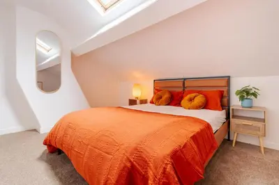 a bedroom with a large bed with orange pillows at Liverpool Luxe Retreat 3 Bedroom House Next to Everton Stadium in Liverpool