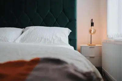 a bed with a green headboard in a bedroom at Liverpool Luxe Retreat 3 Bedroom House Next to Everton Stadium in Liverpool