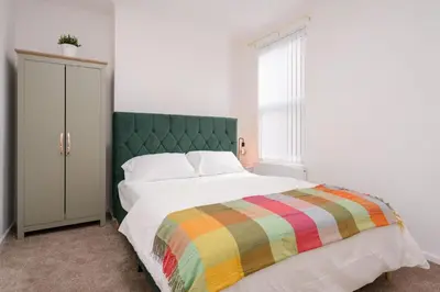 a bedroom with a bed with a green headboard at Liverpool Luxe Retreat 3 Bedroom House Next to Everton Stadium in Liverpool