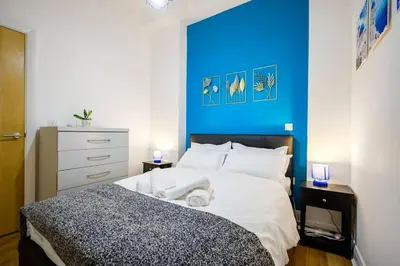 a bedroom with a large bed with a blue wall at Charming Apartment in Liverpool City Centre - Peaceful Sleep! in Liverpool