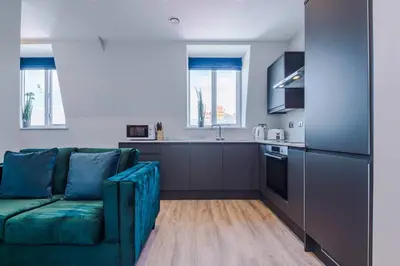 a living room with a couch and a kitchen at Elysée Suites - Chic 1 Bed Flat in Southport in Southport