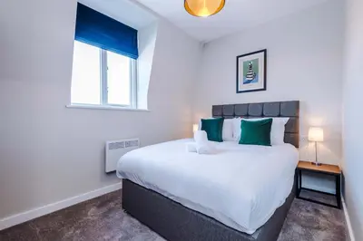 a bedroom with a large white bed with green pillows at Elysée Suites - Chic 1 Bed Flat in Southport in Southport