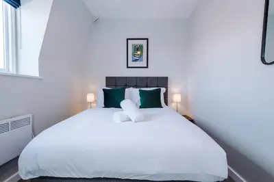 a bedroom with a large white bed with green pillows at Elysée Suites - Chic 1 Bed Flat in Southport in Southport