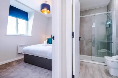 a bedroom with a bed and a shower and a toilet at Elysée Suites - Chic 1 Bed Flat in Southport in Southport