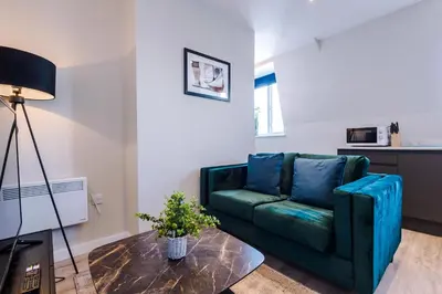 a living room with a green couch and a table at Elysée Suites - Chic 1 Bed Flat in Southport in Southport