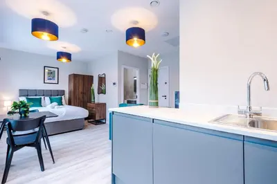 a kitchen with a sink and a bedroom with a bed at Elysée Suites - Spacious Studio in Southport in Southport