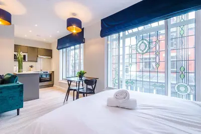 a bedroom with a white bed and a large window at Elysée Suites - Spacious Studio in Southport in Southport