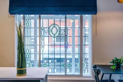 a window with a blue curtain in a room with a table at Elysée Suites - Spacious Studio in Southport in Southport