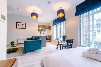a bedroom with a bed and a living room at Elysée Suites - Spacious Studio in Southport in Southport