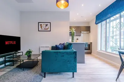 a living room with a blue couch and a tv at Elysée Suites - Spacious Studio in Southport in Southport
