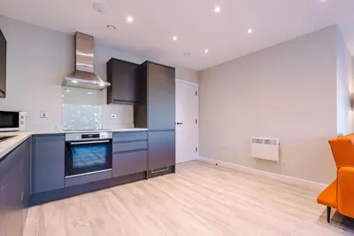 an empty kitchen with blue cabinets and an orange chair at Elysée Suites - Stunning 2 Bed Flat in Southport in Southport