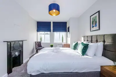 a bedroom with a large white bed with blue curtains at Elysée Suites - Stunning 2 Bed Flat in Southport in Southport