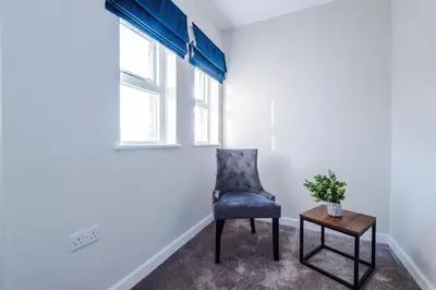 a blue chair sitting in a room with a table at Elysée Suites - Stunning 2 Bed Flat in Southport in Southport