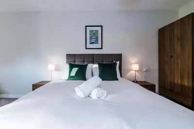 a bedroom with a large white bed with green pillows at Elysée Suites - Stunning 2 Bed Flat in Southport in Southport