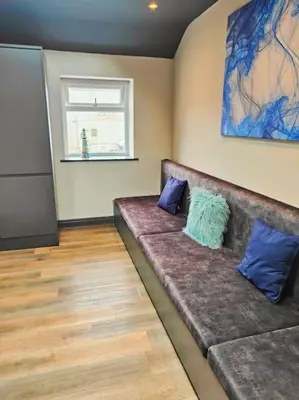 a room with a couch with two blue pillows on it at Sloane modern 2 bedroom seafront Apartment in Blackpool