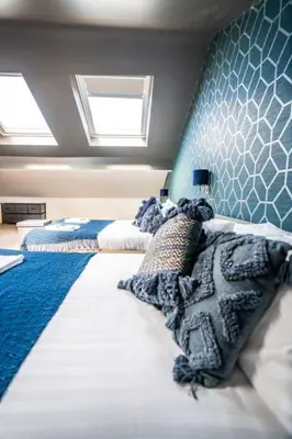 a bedroom with two beds and a blue wall at Belgravia Duplex Seaview Apartment in Blackpool
