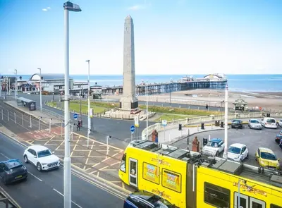 a yellow train in a parking lot next to the beach at Belgravia Duplex Seaview Apartment in Blackpool