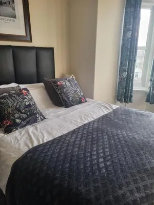 a bed with a gray comforter and pillows in a bedroom at Station Guesthouse - Self entry via keypad inc parking in Lancaster