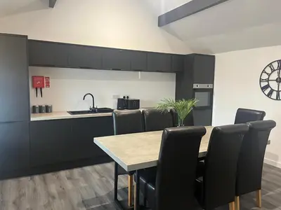 a kitchen with black cabinets and a table and chairs at Apartment Twenty4 Blackpool in Blackpool