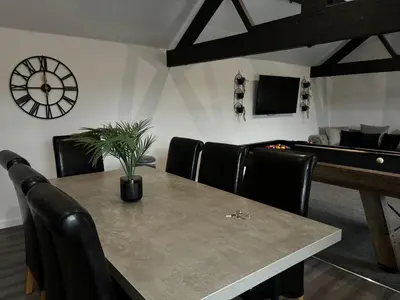 a dining room with a table with chairs and a clock at Apartment Twenty4 Blackpool in Blackpool