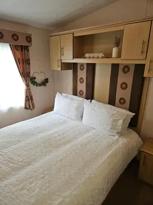 a bedroom with a bed with white sheets and a window at Luxe 6 berth caravan Lytham in Weeton