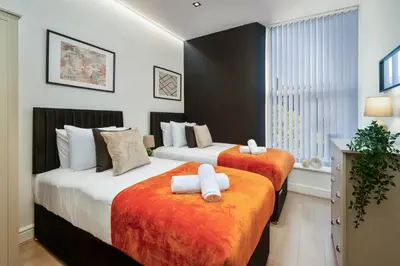 a bedroom with two beds with orange and white sheets at Lombana Apt 4 - City Centre - Parking in Liverpool