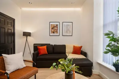 a living room with a black couch and orange pillows at Lombana Apt 4 - City Centre - Parking in Liverpool