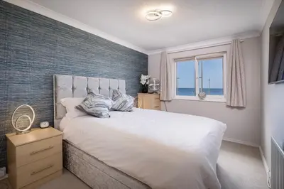 a bedroom with a large white bed with a window at The Beachcomber - seafront, free parking, free wifi in Cleveleys