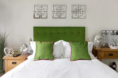 a bedroom with a bed with green and white pillows at heft view at rose cottage - opp heft restaurant in Grange Over Sands