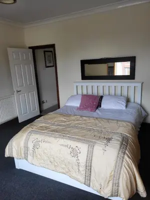 a bedroom with a large bed with a mirror on the wall at Cosy cottage in Chorley