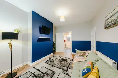a living room with a couch and a blue accent wall at Spacious 3-Bedroom Liverpool Home Sleeps 6 Great Transport Links in Liverpool