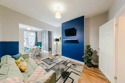 a living room with a couch and a blue wall at Spacious 3-Bedroom Liverpool Home Sleeps 6 Great Transport Links in Liverpool