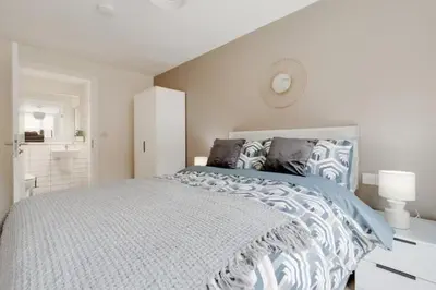 a white bedroom with a large bed with blue and white sheets at Richmond Row Apartments - Free On-Site Parking, WiFi & EV in Liverpool