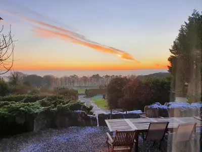 a table and chairs with a sunset in the background at Bayview House Silverdale in Silverdale