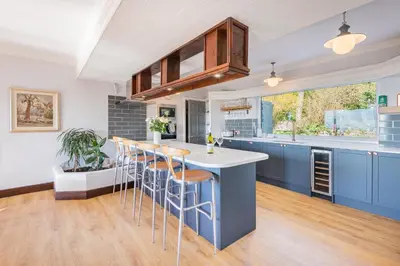 a kitchen with blue cabinets and a bar with stools at Bayview House Silverdale in Silverdale