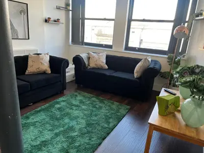 a living room with two black couches and a green rug at Mathew Street 1 bed apt sleeps 6 in Liverpool