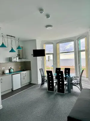 a dining room with a table and chairs and a kitchen at The Charlton - Aparthotel in Blackpool